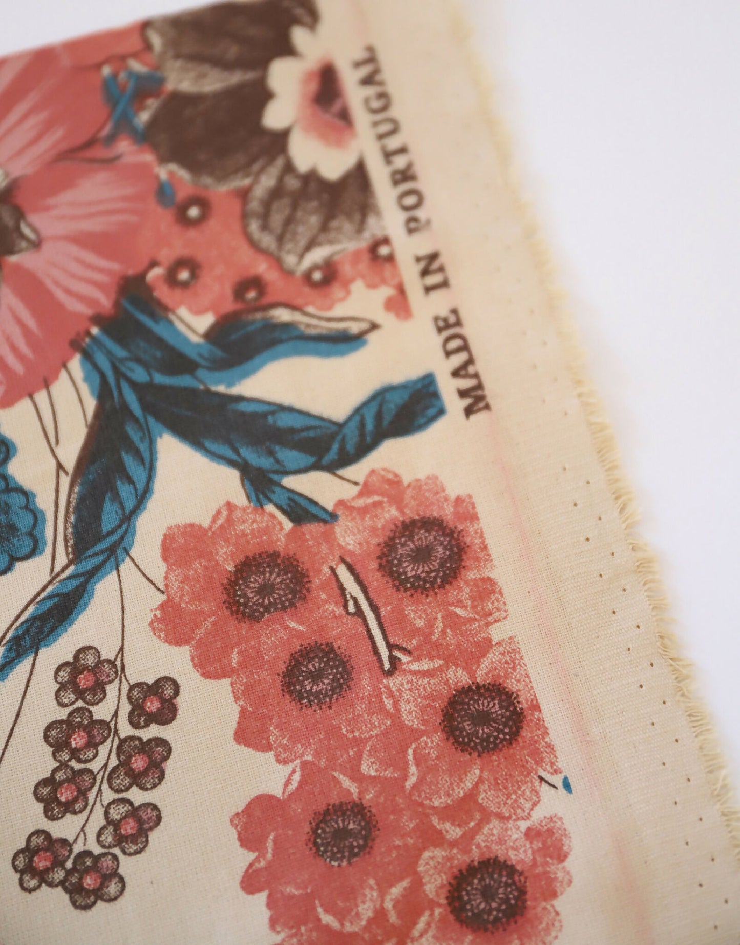 Abat-jour fleuri : tissu crème avec gros plan de fleurs rouges et inscription “MADE IN PORTUGAL”.