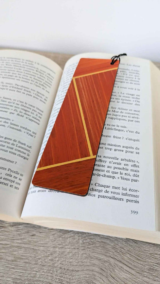 Marque-page orange en marqueterie de paille, ficelle noire nouée sur un livre