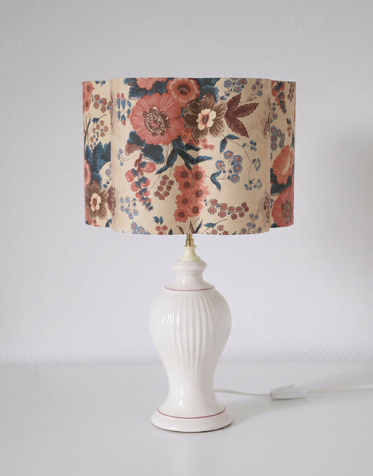 Abat-jour fleuri crème et multicolore, posé sur une lampe blanche avec interrupteur.