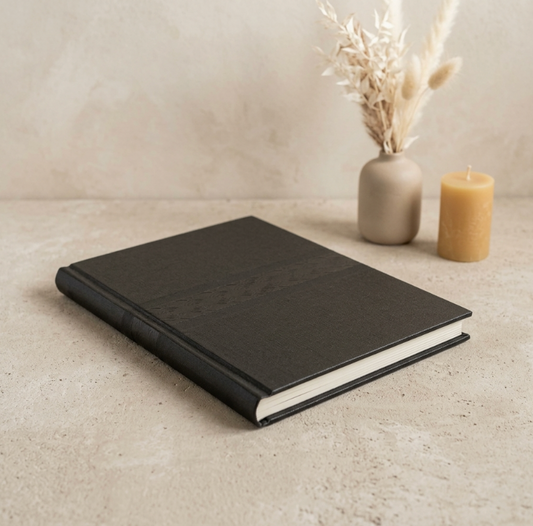 Carnet noir fermé, couverture grainée et tranche claire visibles