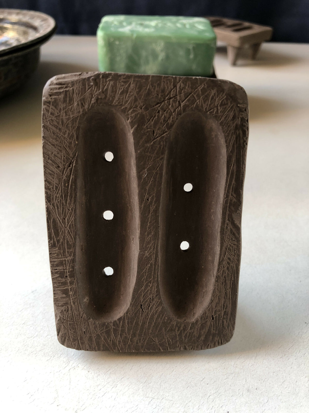 Porte-savon en bois sombre avec deux ouvertures ovales percées