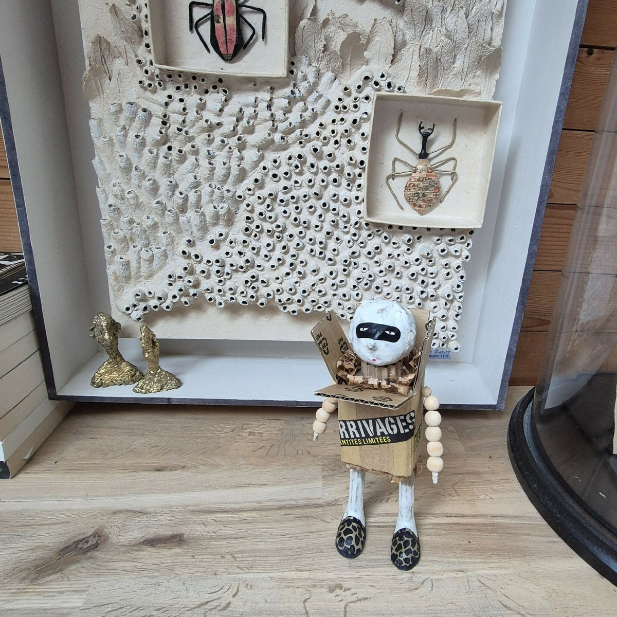 Sculpture bonhomme en carton exposé en vitrine murale, tête blanche et chaussures léopard