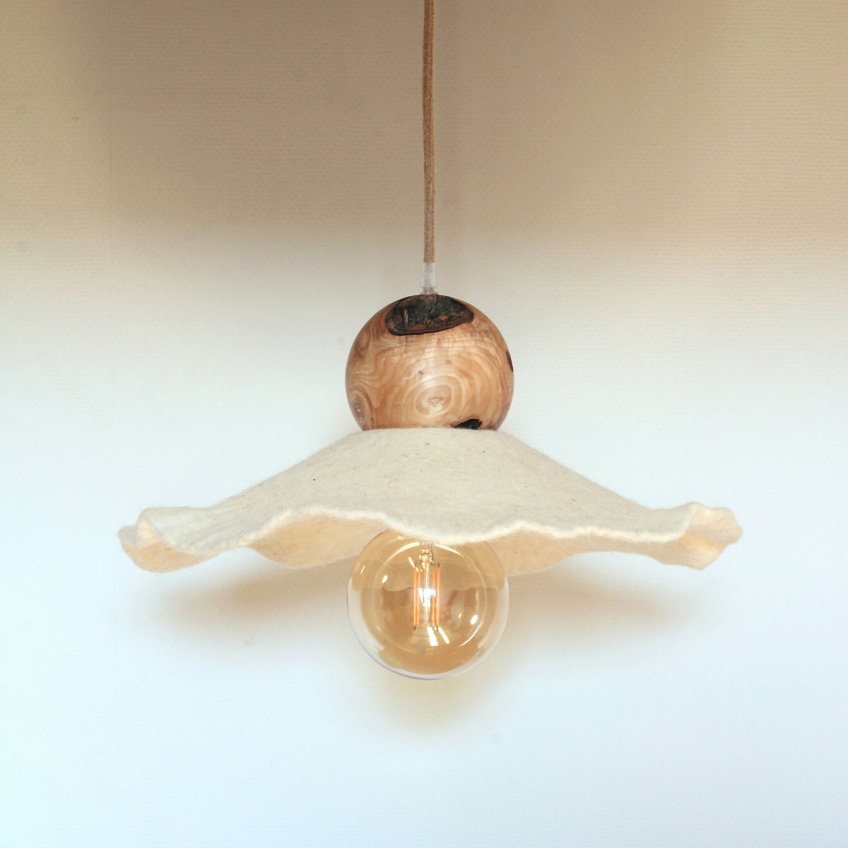 Suspension lumineuse : sphère en bois et ailes en feutre de laine, ampoule visible.
