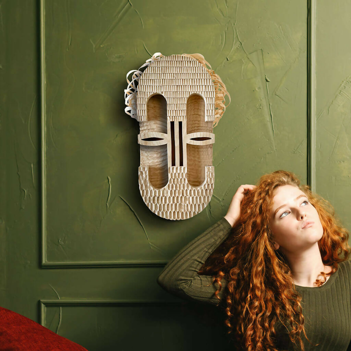 Masque décoratif en fibres de paille tressées fixé au mur, modèle visage stylisé.