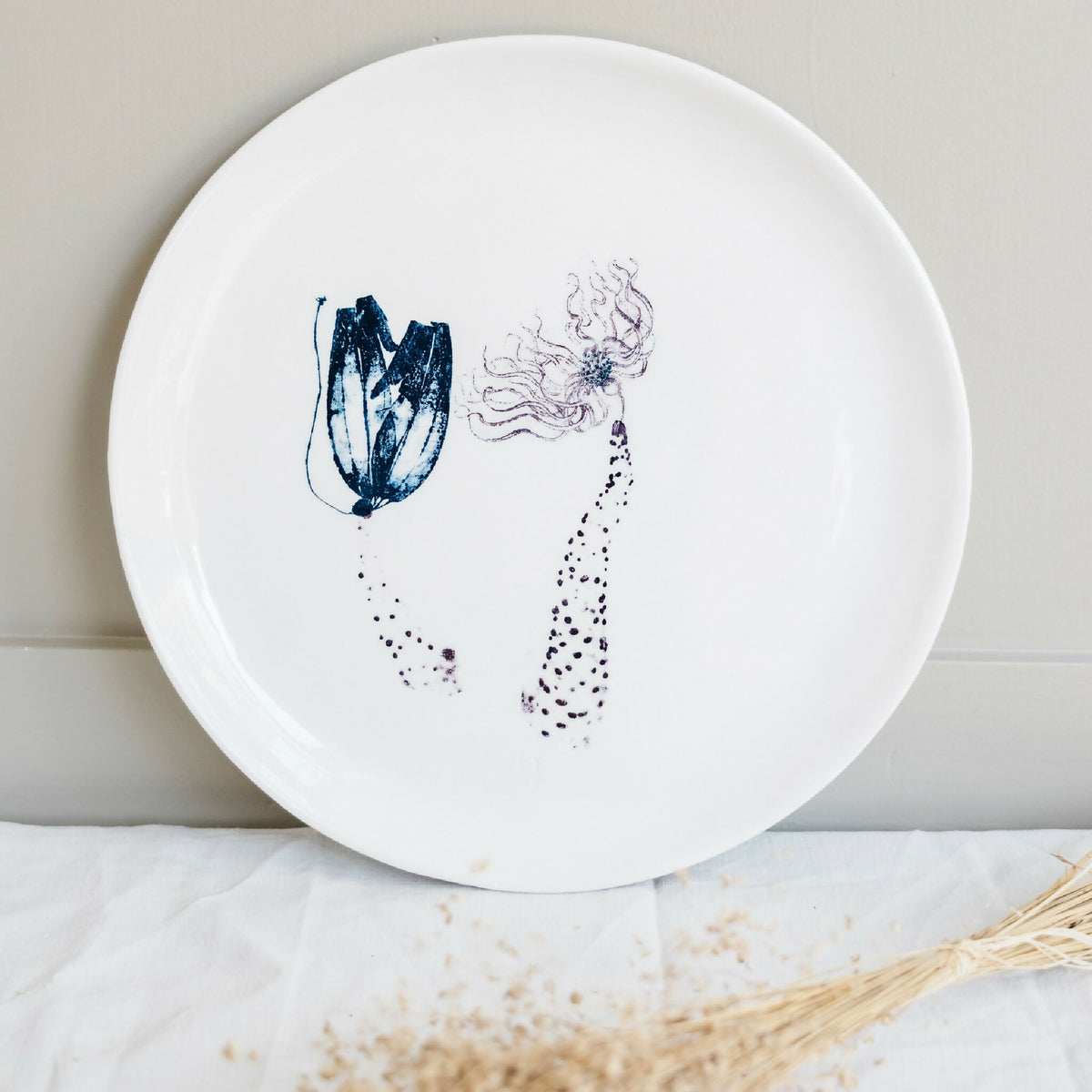 Plat rond en porcelaine blanche fait main, décor abstrait bleu avec éclaboussures.