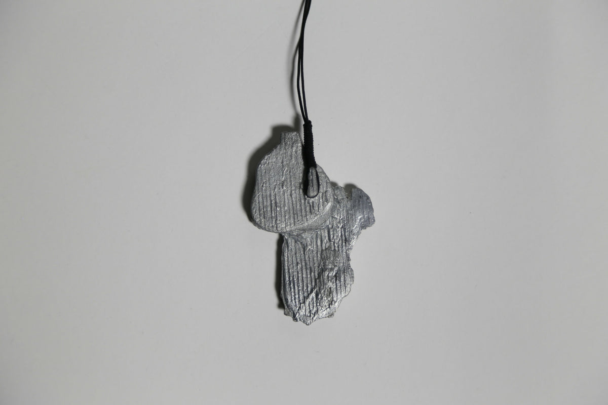Pendentif gris en forme de feuille, texture nervurée, sur cordon noir.