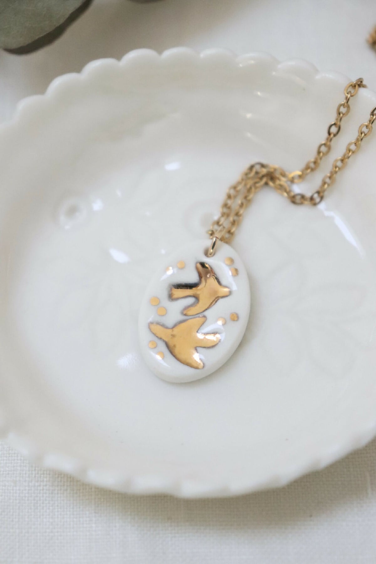 Collier en porcelaine : médaillon ovale blanc avec hirondelles dorées, chaîne dorée