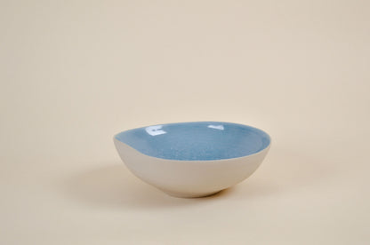 Coupe en céramique blanche à intérieur bleu, vue en biais, bord évasé.
