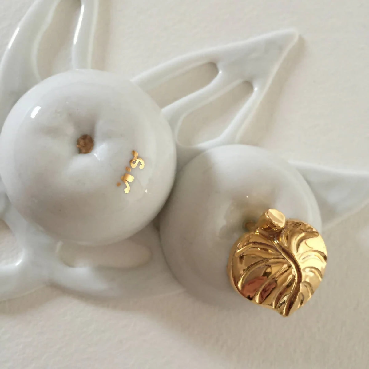 Boîte en porcelaine blanche ajourée avec pommes, bouton doré et détails de surface