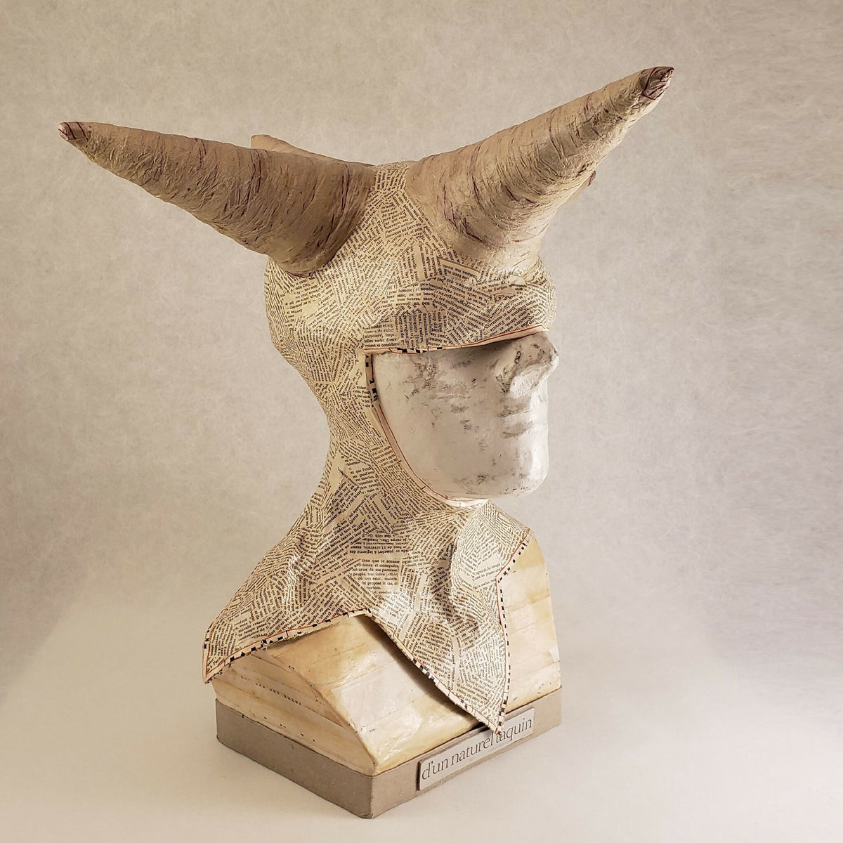 Buste sculpté beige à cornes, visage en demi-profil, inscription « d’un naturel taquin » sur la base