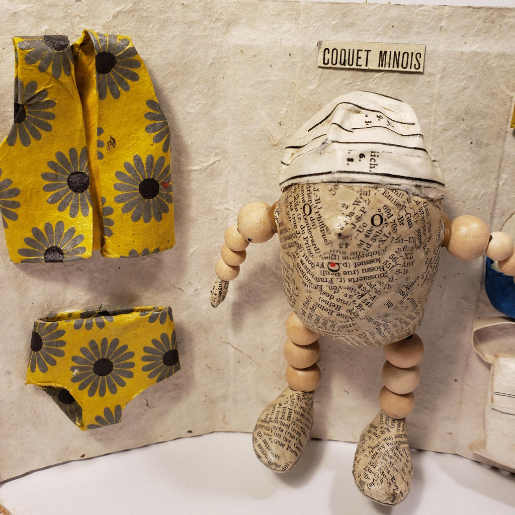 Sculpture Coquet minois : figurine sur panneau en carton, vêtements jaunes à motifs