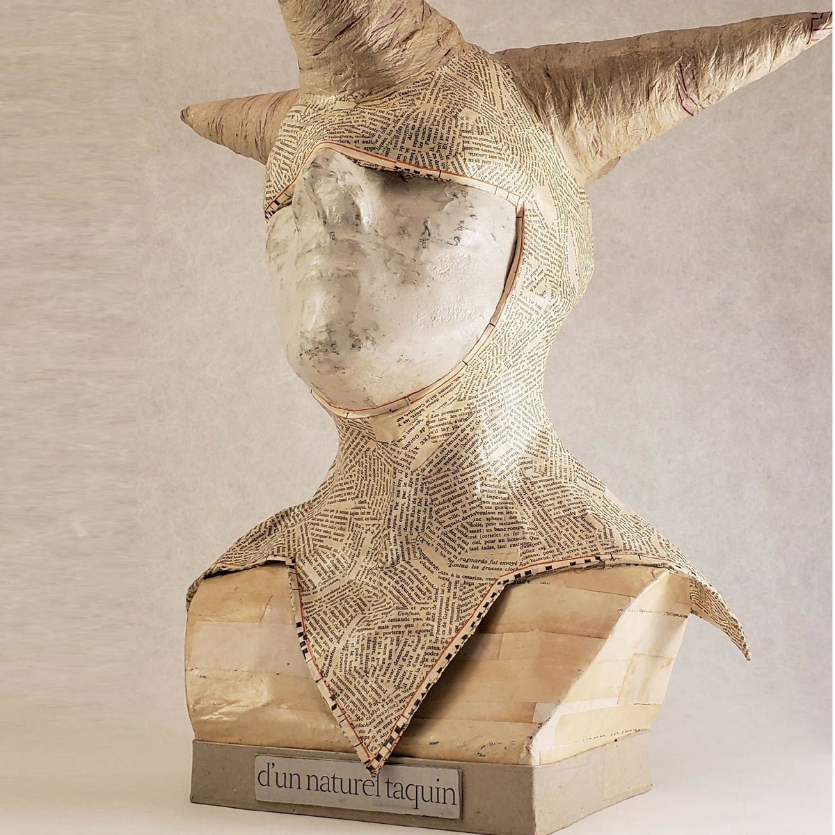 Buste sculpté en papier texturé beige, gros plan visage et cornes, base « d’un naturel taquin »