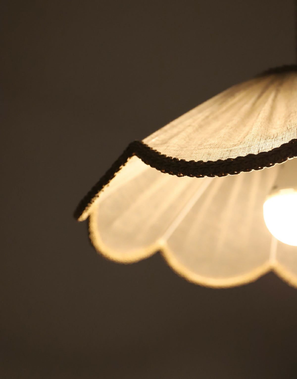 Suspension florale beige : détail du bord ondulé tressé sur abat-jour allumé