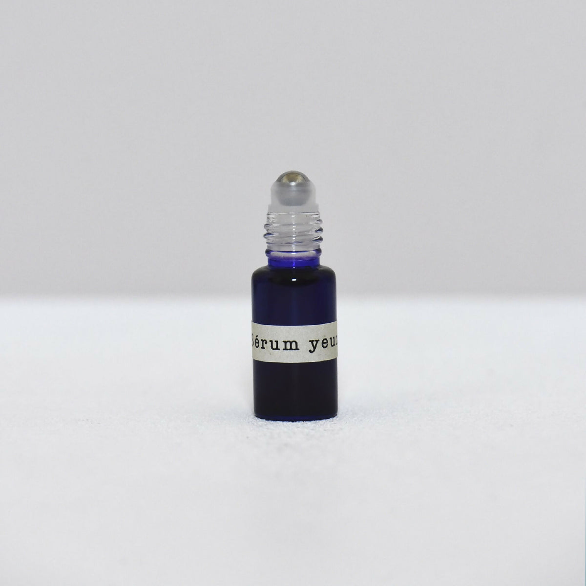 Flacon de sérum pour les yeux avec compte-gouttes et bouchon noir sur base bleu