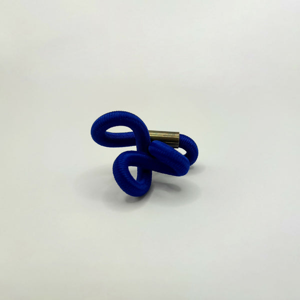 Broche en entrelacs de tissu bleu et tige métallique dorée.