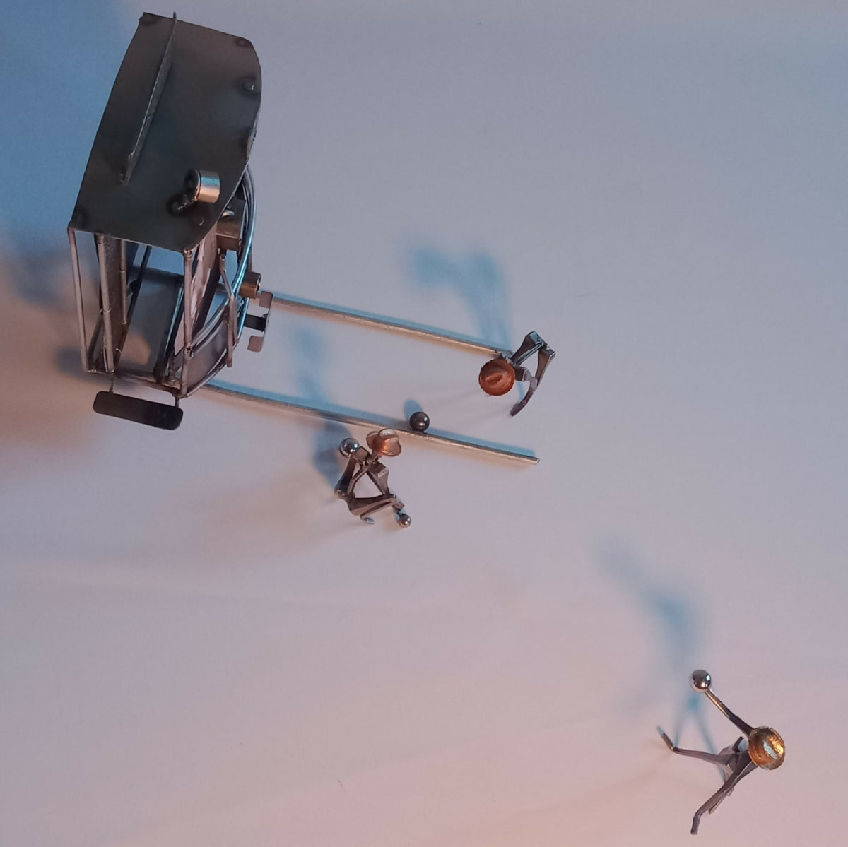 Sculpture miniature en métal : cabine et figurines sur base, vue de côté
