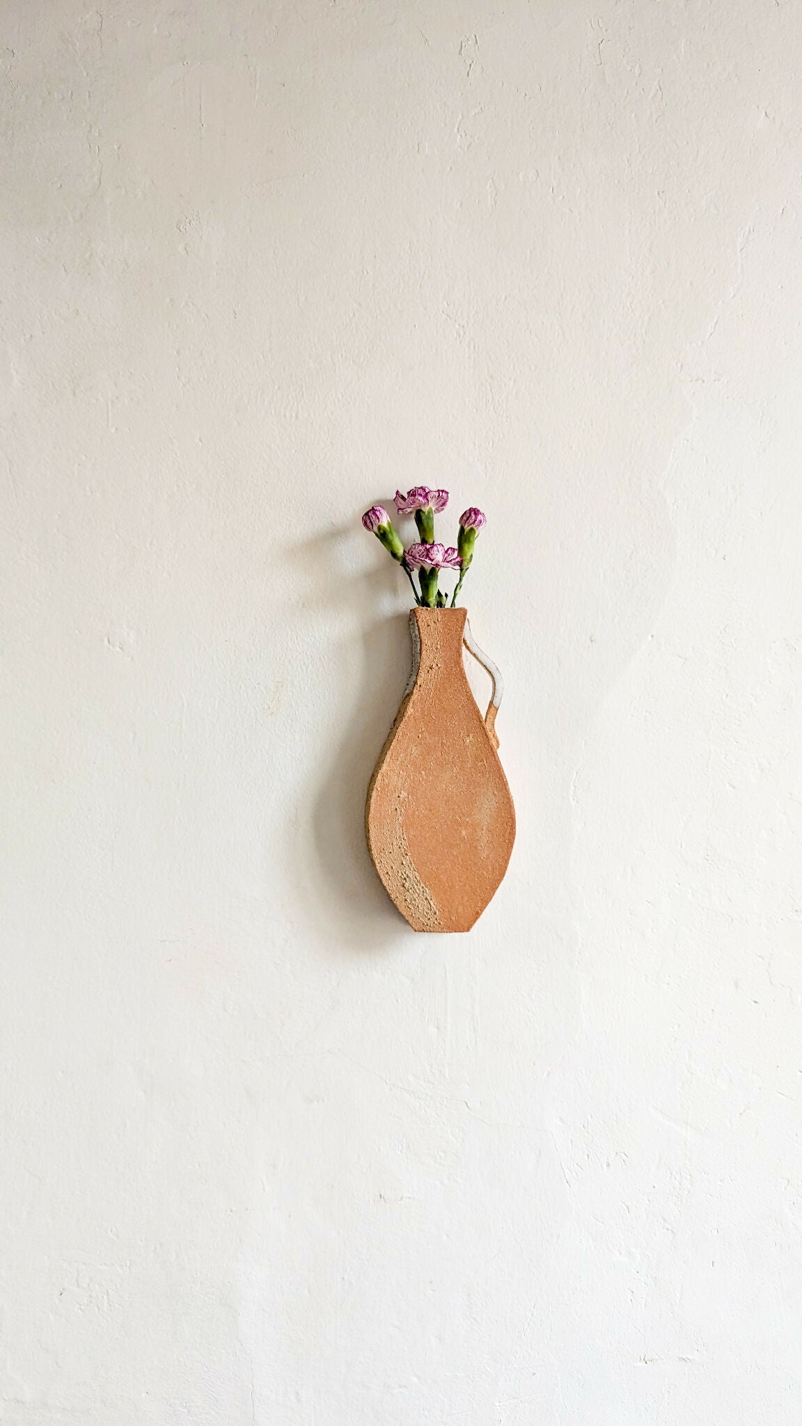 Vase mural en terre cuite en forme de goutte, avec bouquet de fleurs violettes
