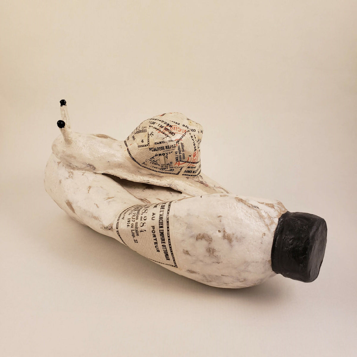 Sculpture d’escargot blanc en papier imprimé, corps en relief et pointe noire.