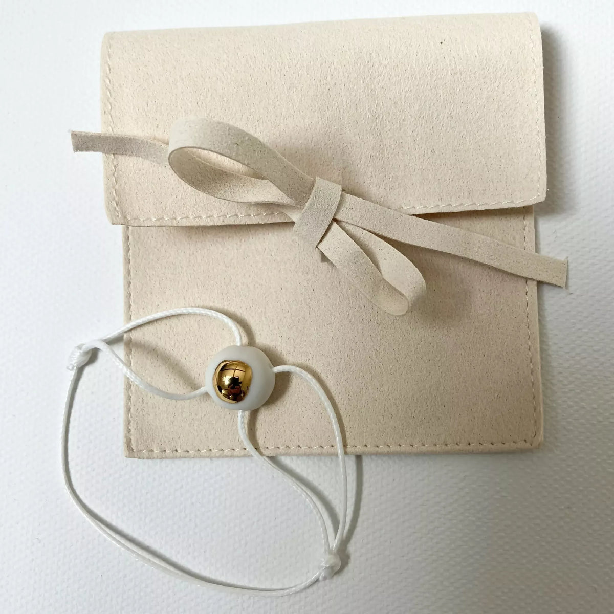 Bracelet en cordon blanc avec perle dorée et pochette cadeau beige