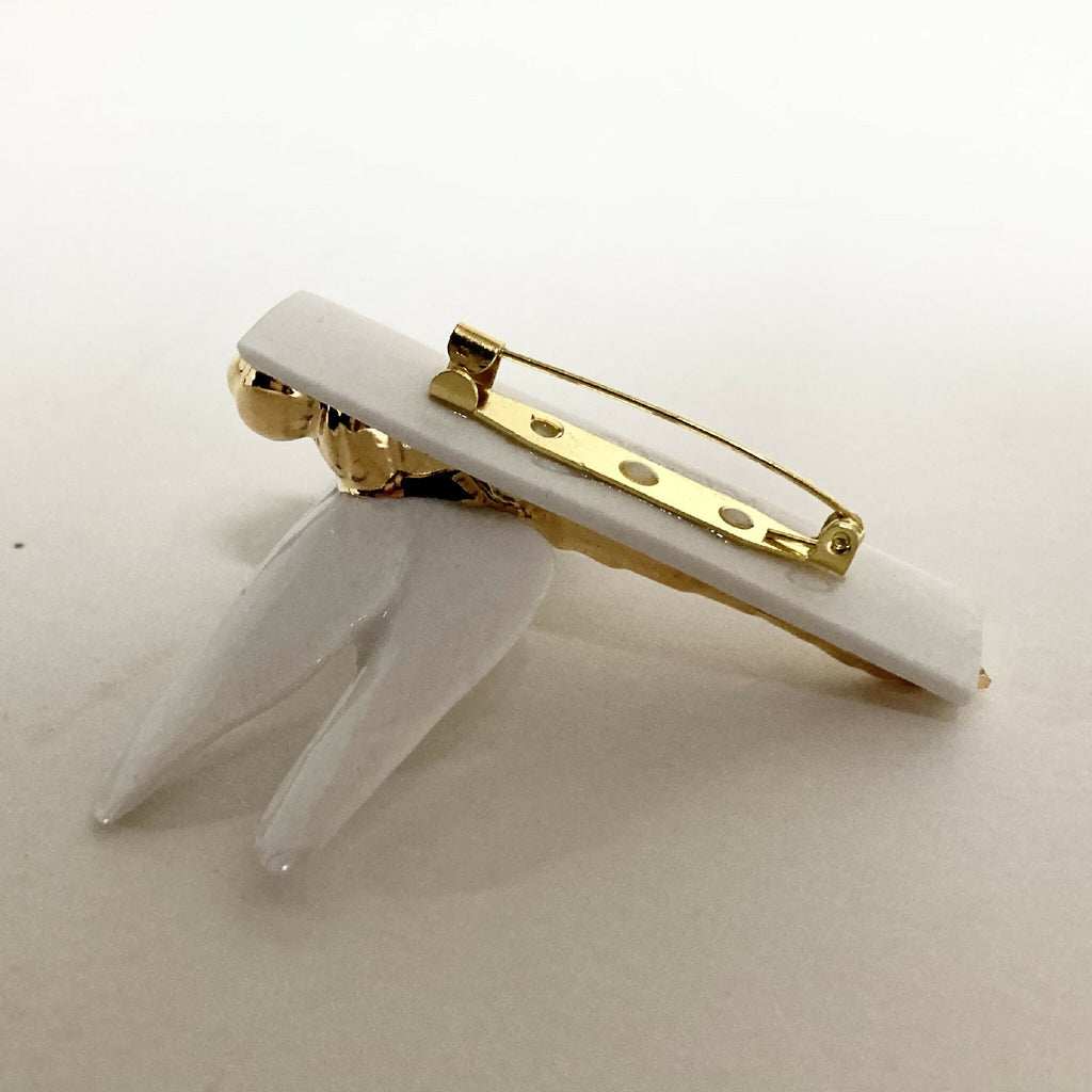 Broche libellule vue arrière, fermoir doré et tige métallique sur support blanc
