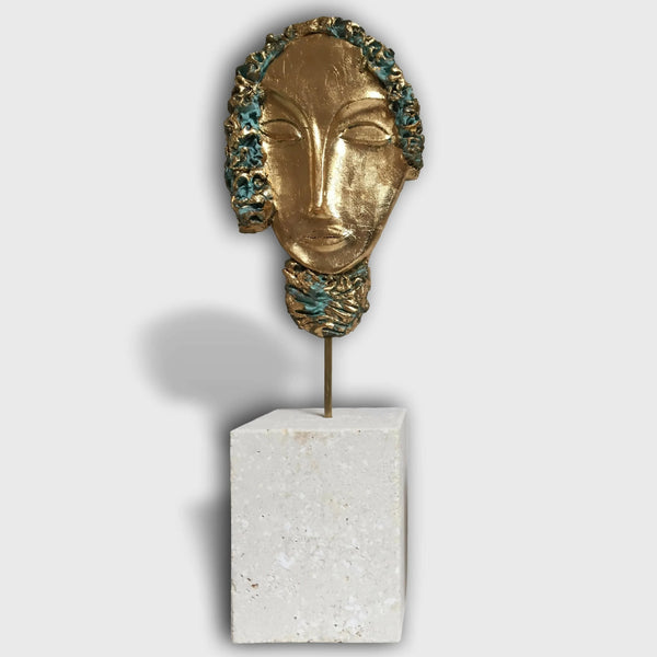 Sculpture de visage d’Aphrodite : masque doré sur socle en pierre blanche