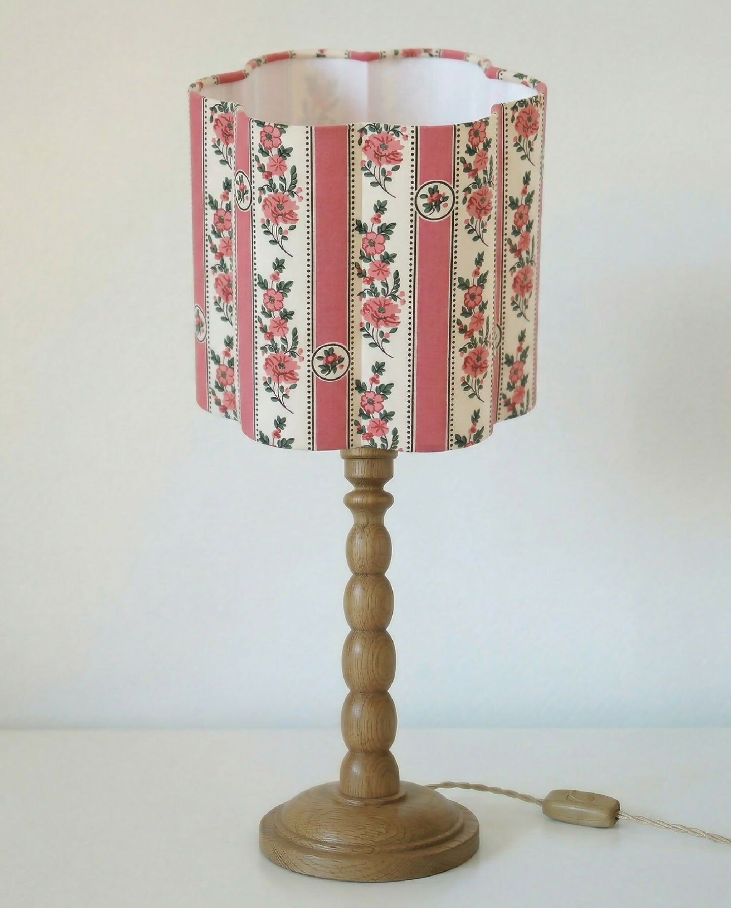 Abat-jour forme fleur à motifs floraux et rayures roses, sur pied en bois.