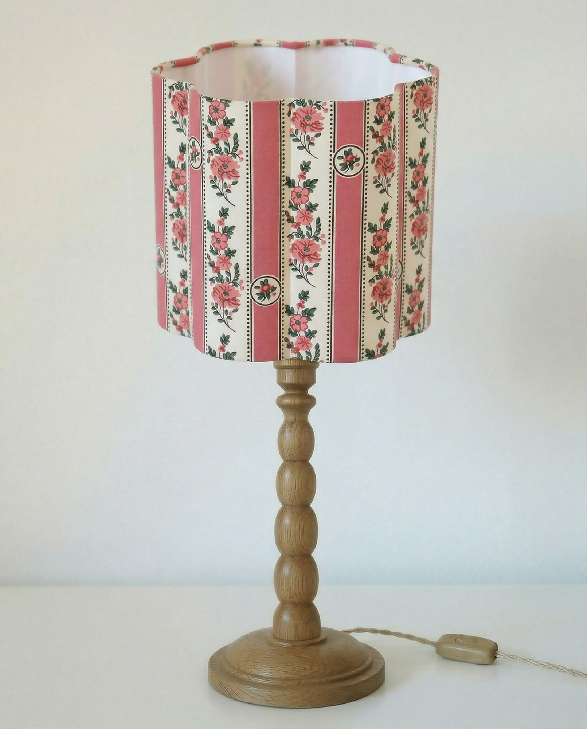 Abat-jour forme fleur à motifs floraux et rayures roses, sur pied en bois.