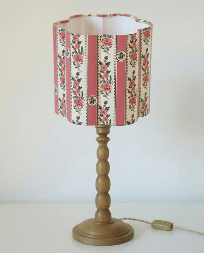 Abat-jour forme fleur à motifs floraux et rayures roses, sur pied en bois.