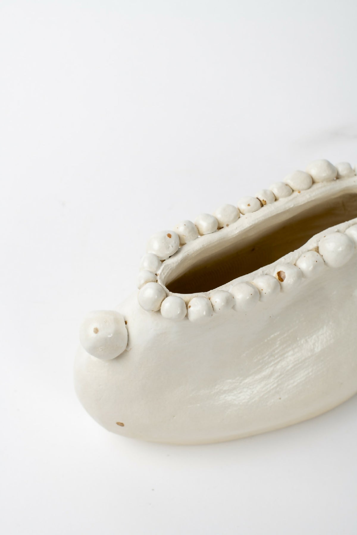 Vase en céramique blanche, gros plan de l’intérieur avec bord perlé et pointe latérale