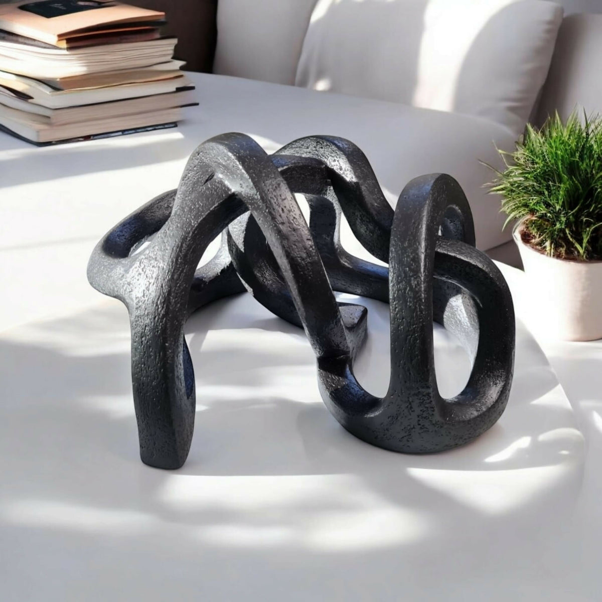 Sculpture abstraite en argile sombre, vue en perspective des anneaux entrelacés.