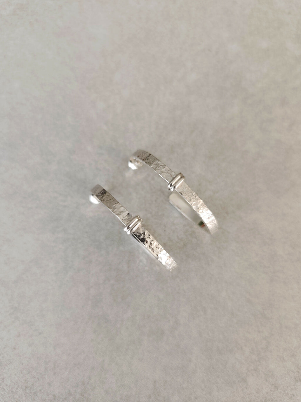 Paire de boucles d’oreilles courbes argentées, texture granuleuse sur la tige