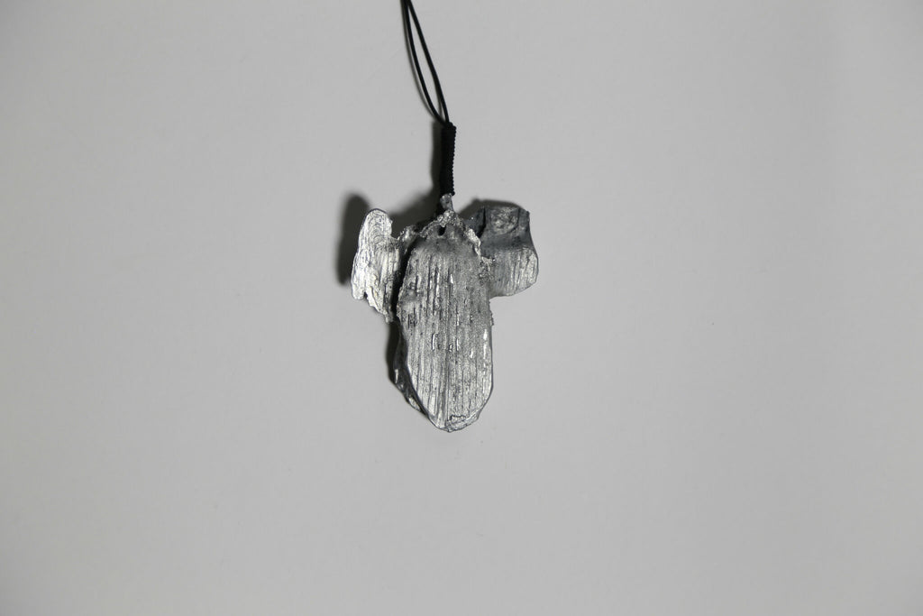 Pendentif gris argenté en forme de feuille d’arbre, vue rapprochée, sur cordon.