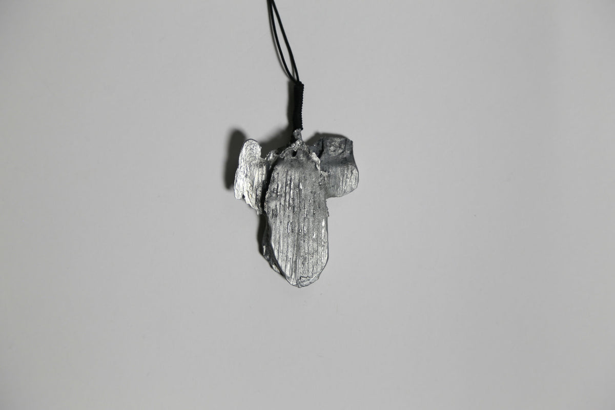 Pendentif gris argenté en forme de feuille d’arbre, vue rapprochée, sur cordon.