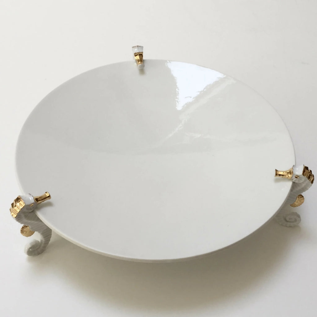 Centre de table hippocampe : grande assiette blanche avec tige centrale et supports d’hippocampes.