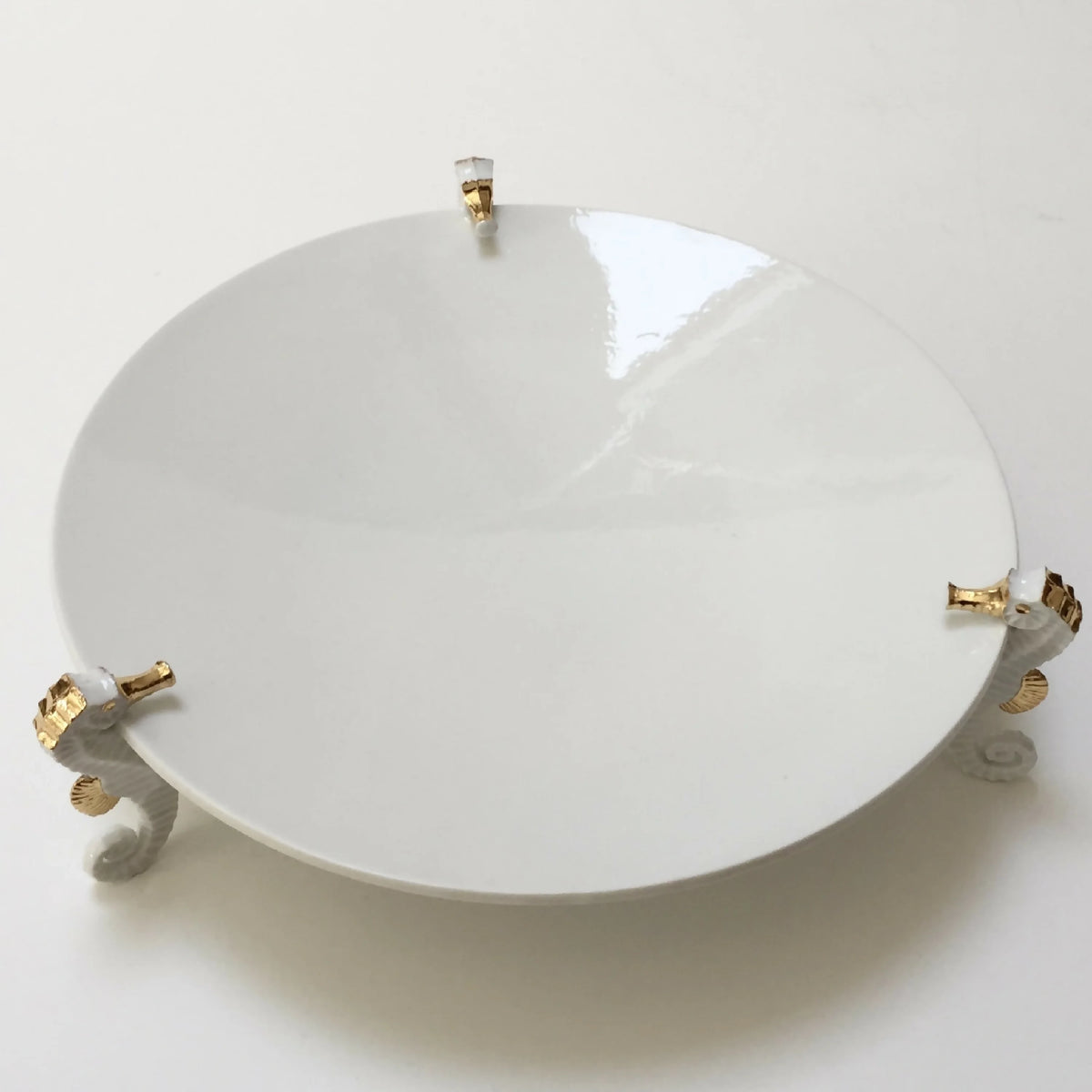Centre de table hippocampe : grande assiette blanche avec tige centrale et supports d’hippocampes.