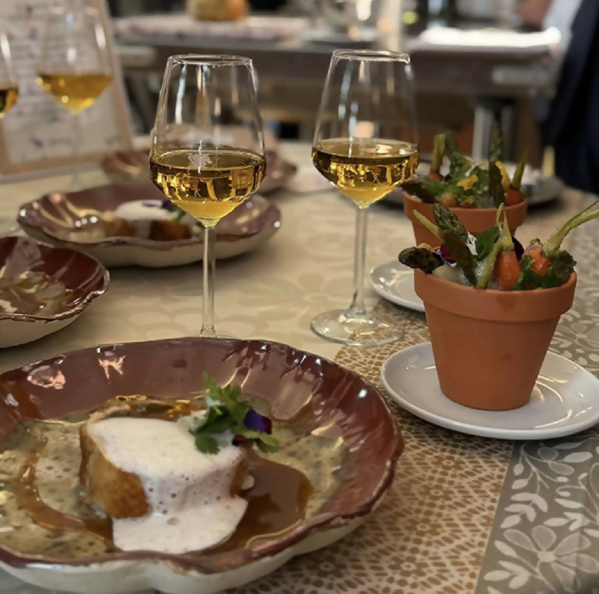 Assiette Prunelle bord brun, garniture : crème blanche et herbes sur décor vert moucheté.