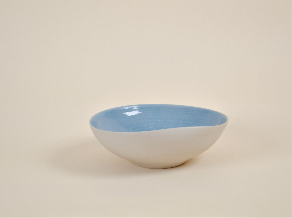 Coupe en céramique blanche à intérieur bleu, forme arrondie, bord évasé.