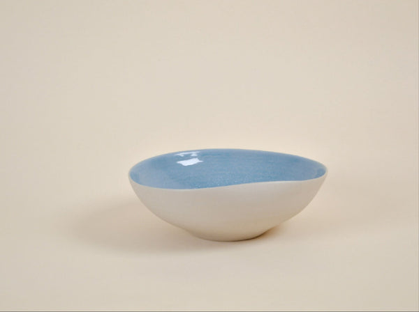 Coupe en céramique blanche à intérieur bleu, forme arrondie, bord évasé.