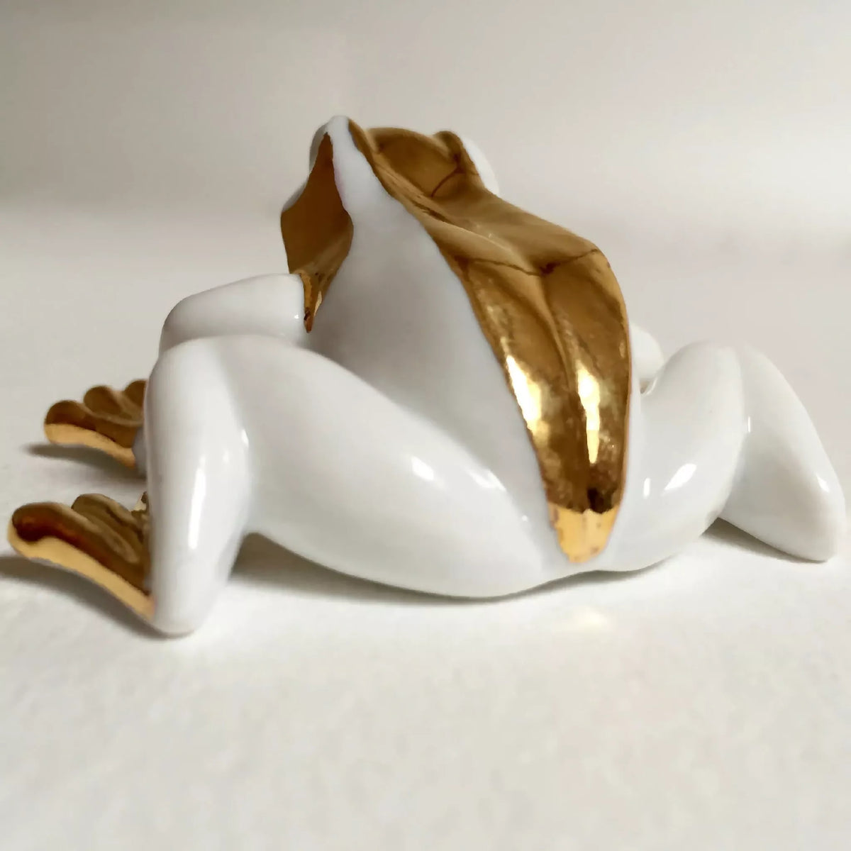 Figurine de grenouille en porcelaine blanche, vue latérale avec bande dorée