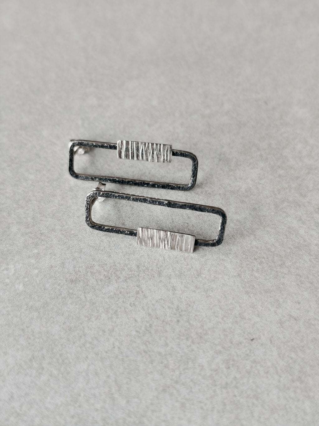 Boucles d’oreilles rectangulaires vues de côté, contours foncés et plaquettes striées