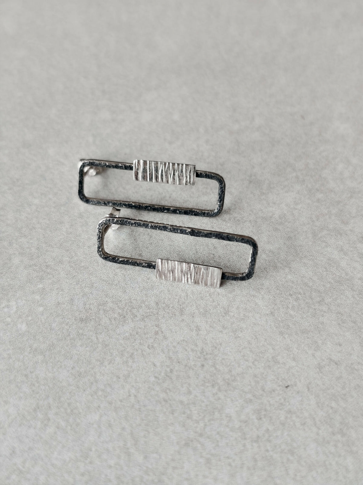 Boucles d’oreilles rectangulaires vues de côté, contours foncés et plaquettes striées
