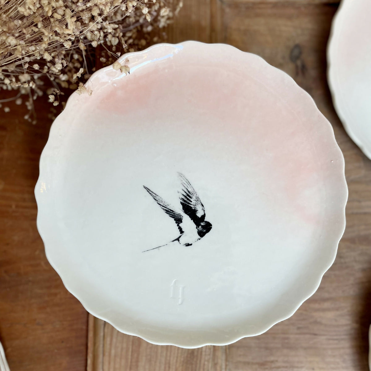 Assiette à dessert en porcelaine blanche, bord festonné, oiseau noir en vol, détail peint