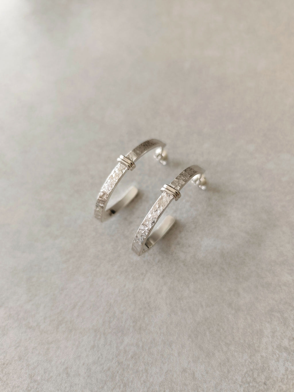Boucles d’oreilles courbes en métal argenté, vues de face avec fermoirs