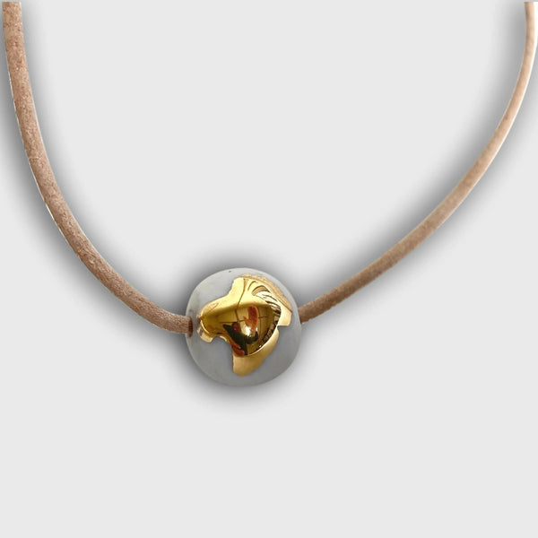 Collier en porcelaine avec pendentif goutte dorée sur cordon brun.