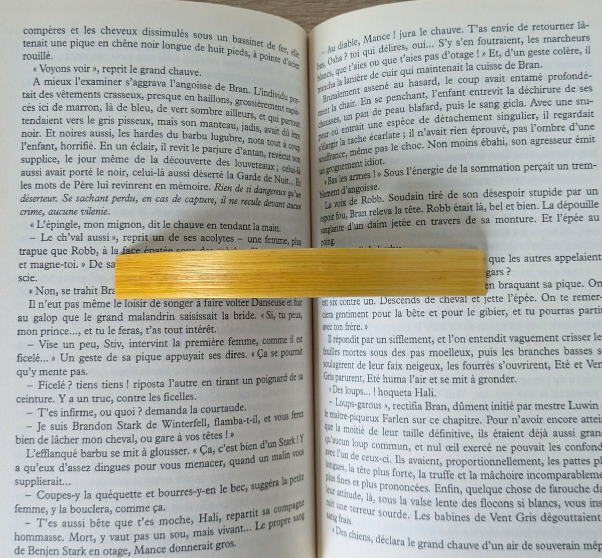 Anneau de lecture en marqueterie de paille jaune sur bois sombre, détail du trou.