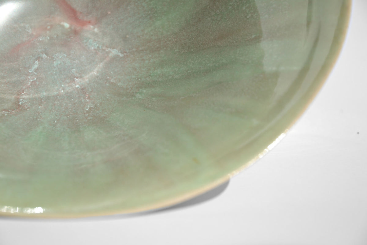 Coupe en céramique, intérieur vert marbré avec éclat et texture, gros plan du bord.