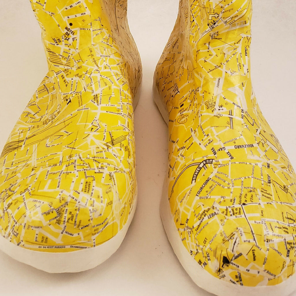 Bottes jaunes à tige haute, motif imprimé sur le dessus, semelle blanche visible.