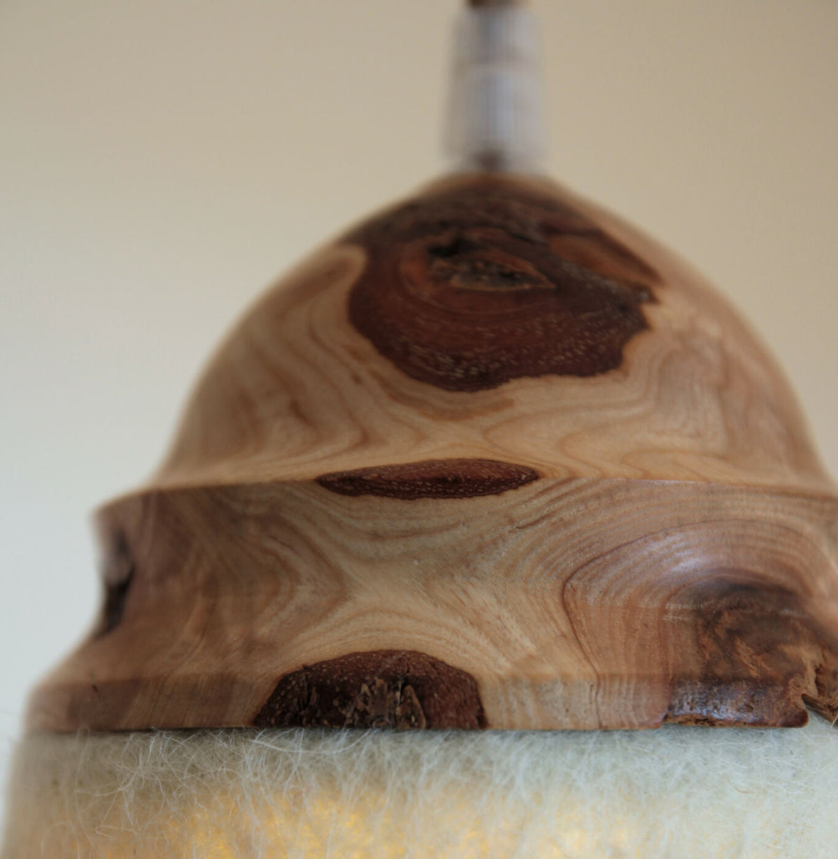 Suspension : vue rapprochée de la couronne en bois brun et du bord en feutre beige