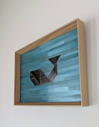 Tableau en marqueterie bleu, formes géométriques anthracite, cadre bois clair.