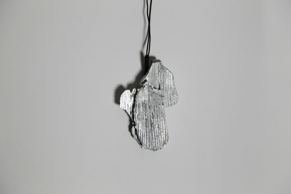 Pendentif gris argenté en forme de feuille, vue de dessus, sur cordon.